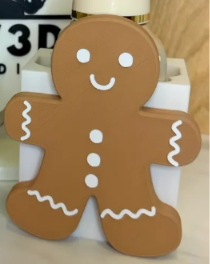 Brown gingerbread man interchangeable cover with white eyes, smile, three buttons, and icing-style trim; base and soap bottle sold separately.