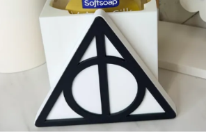Black and white triangular Deathly Hallows symbol cover with circle and vertical line. Soap bottle and base shown are not included.