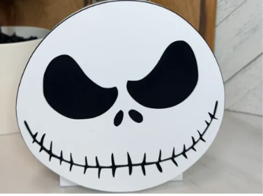 Round white skeleton face cover with black eye sockets, nose, and stitched smile. Base sold separately.